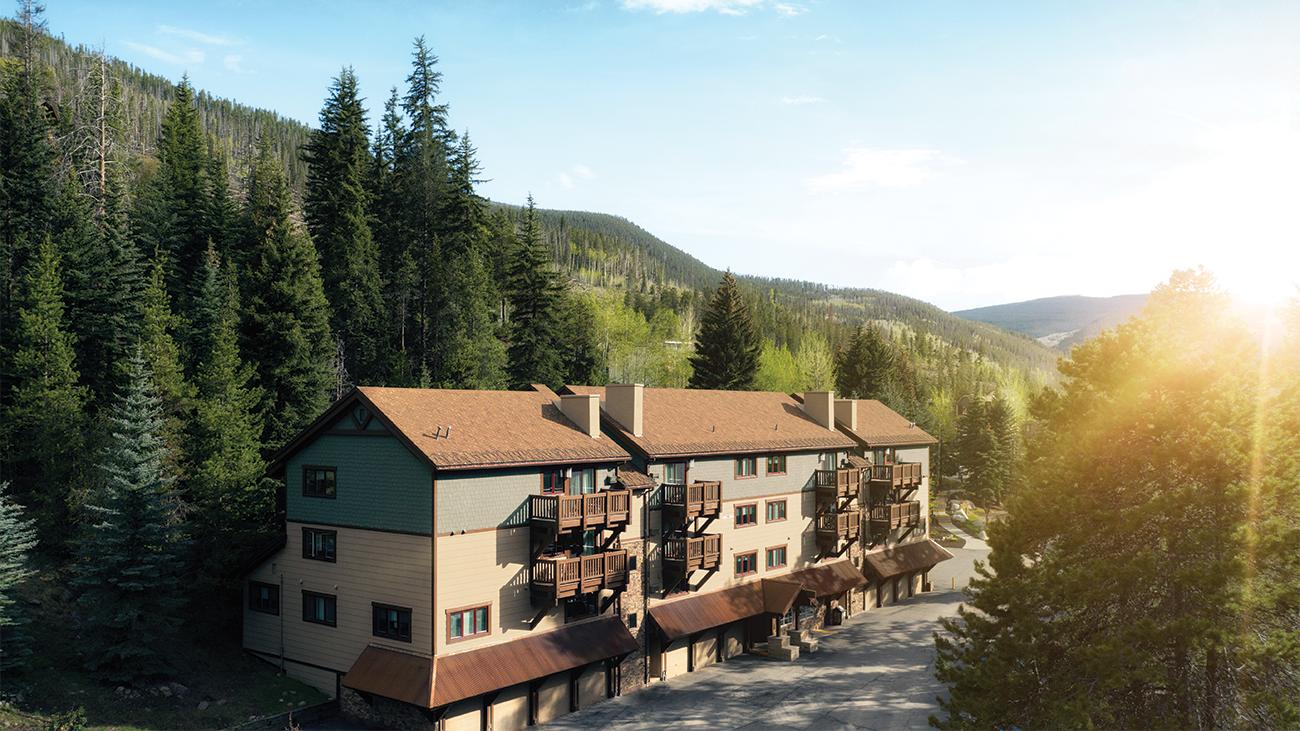 Exterior of Marriott's StreamSide Birch resort timeshare framed by towering trees with mountains in the distance